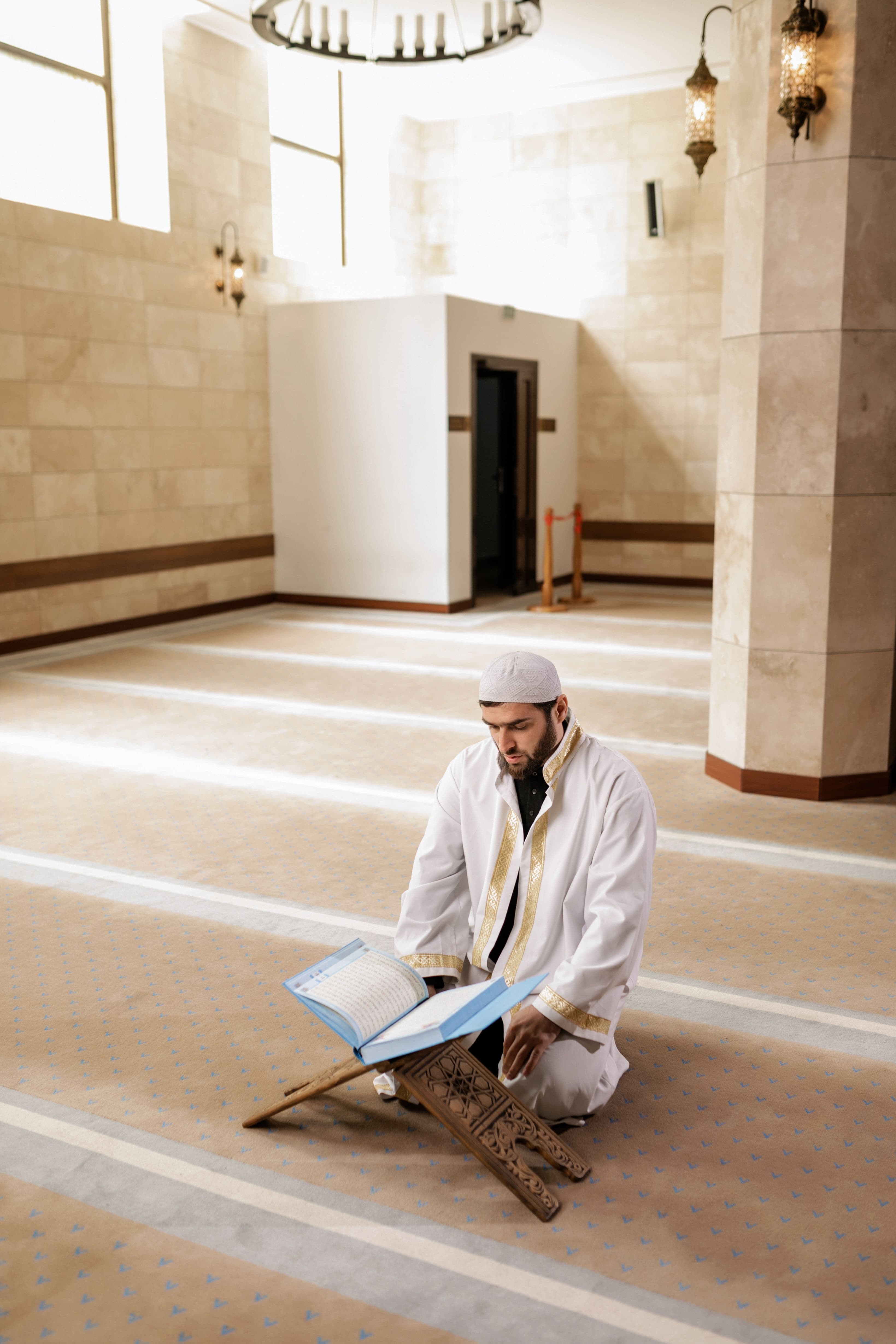 A student reading the Quran on a wooden stand during a quiet study session