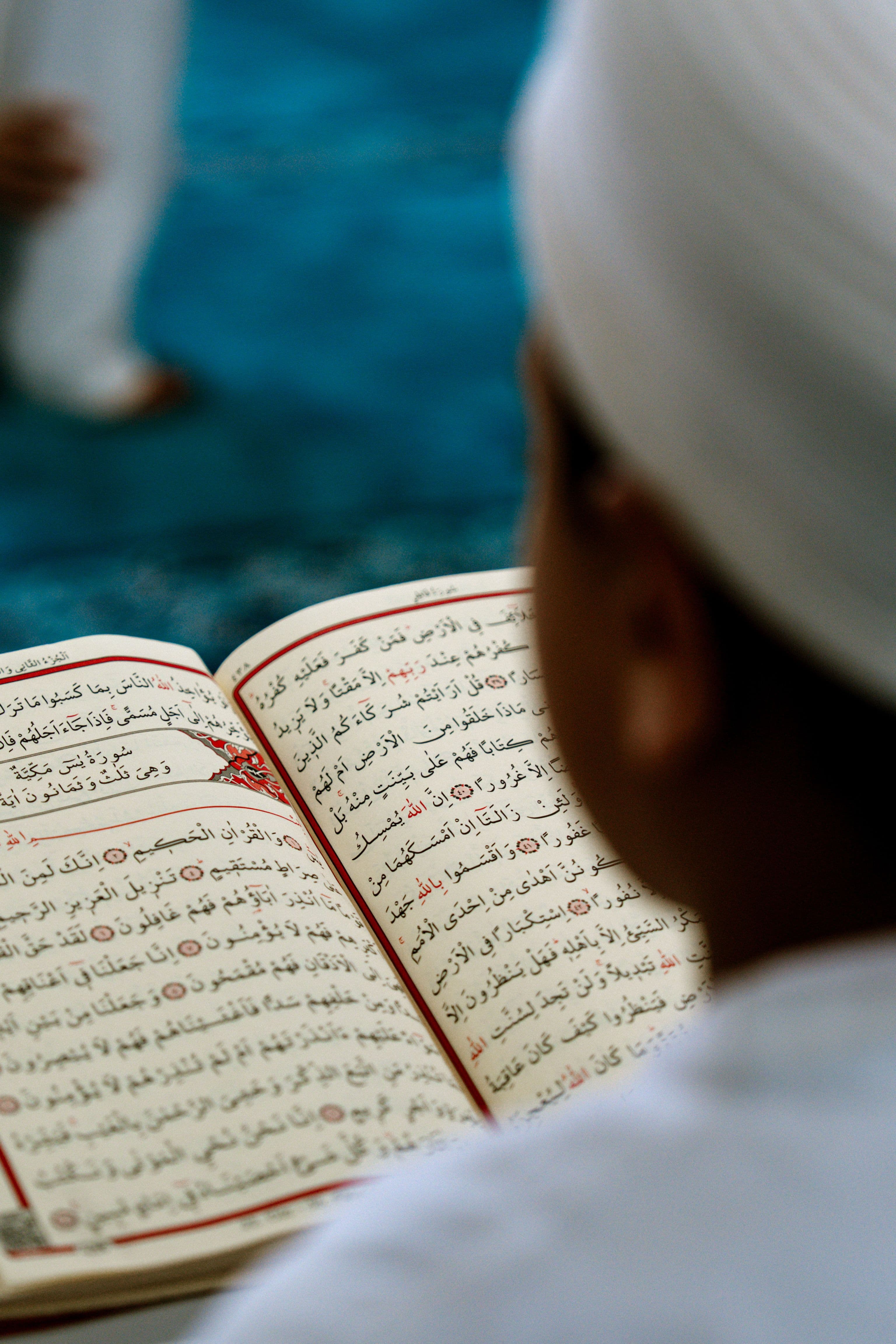 A student reading an open Quran, following the Arabic text