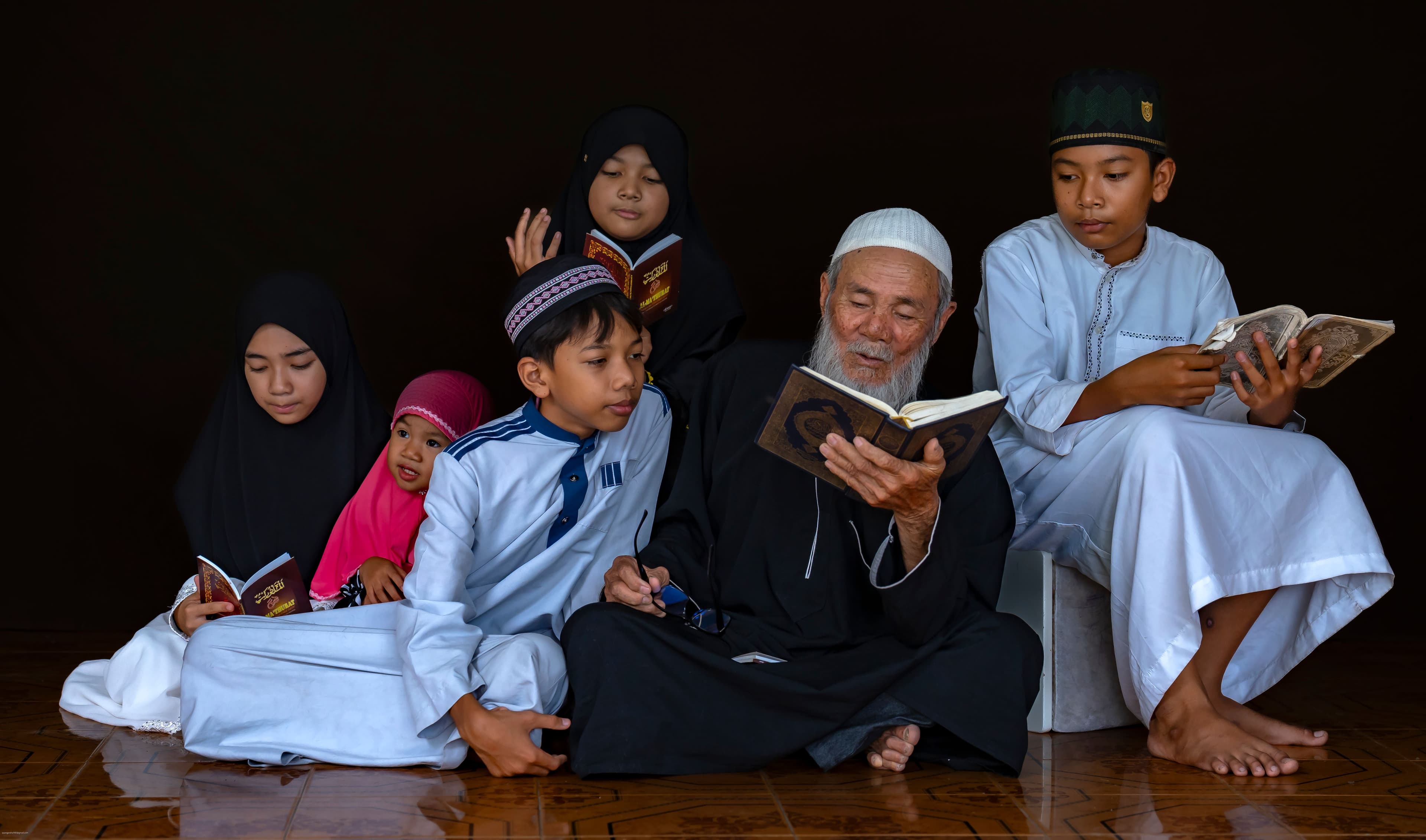 Girls and boys studying the Quran together with their teacher