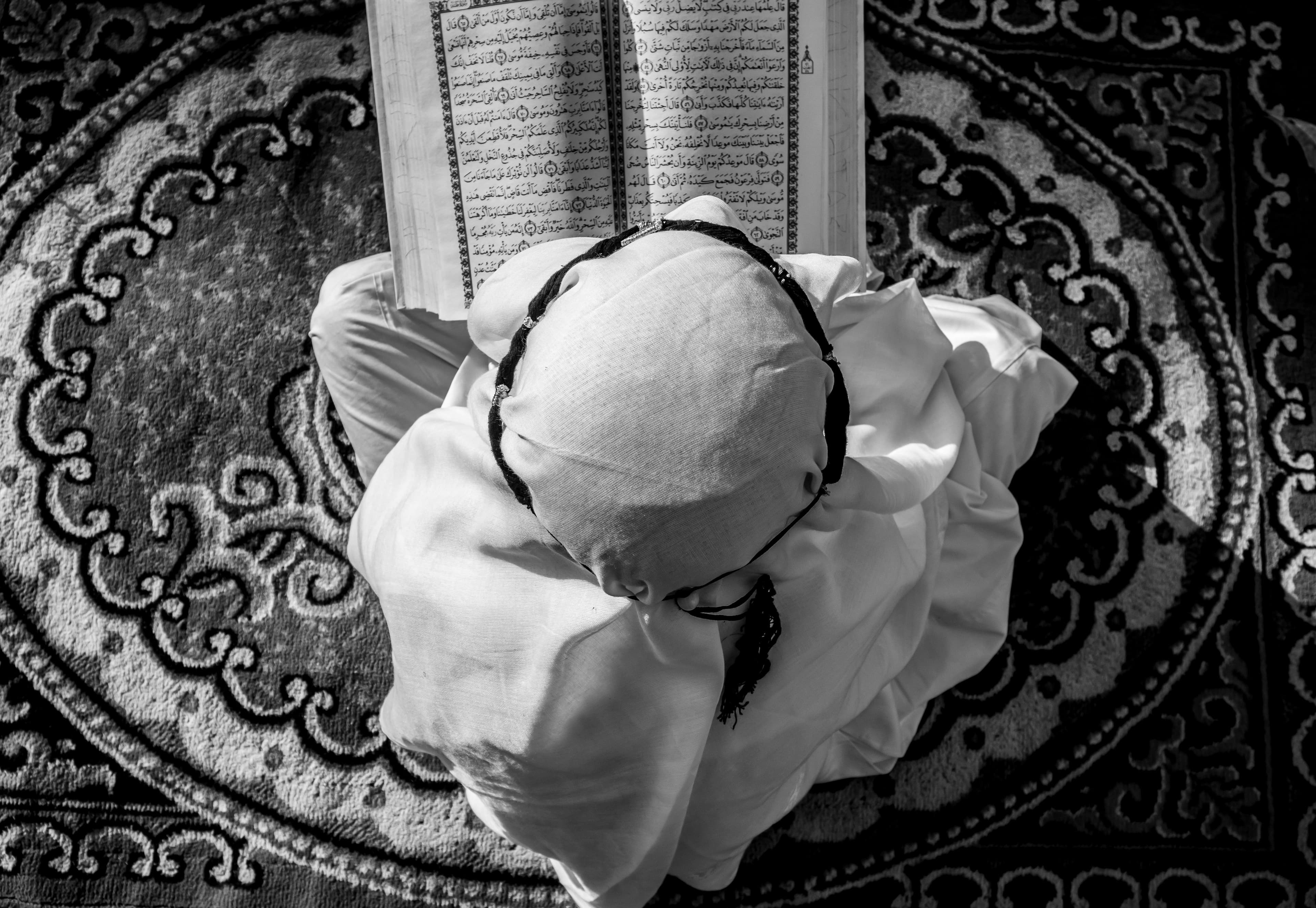 A student closely following the Quran text during recitation practice