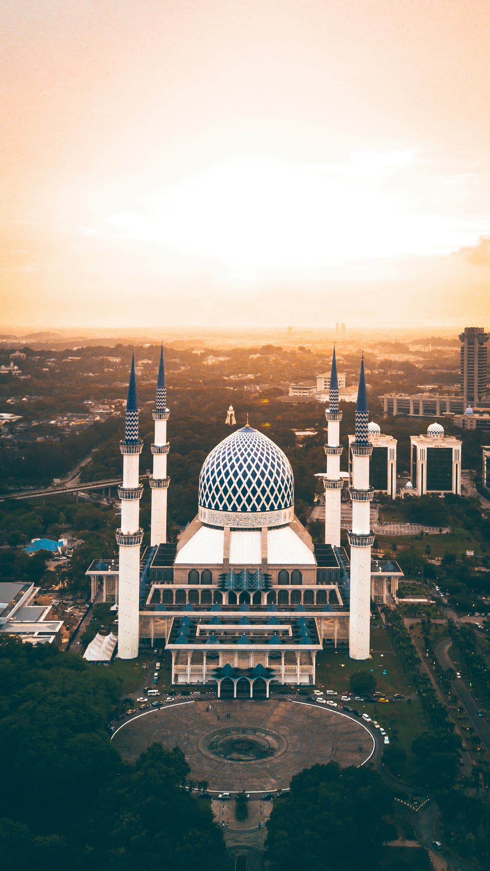 Aerial view of a mosque with a blue dome and minarets at sunset
