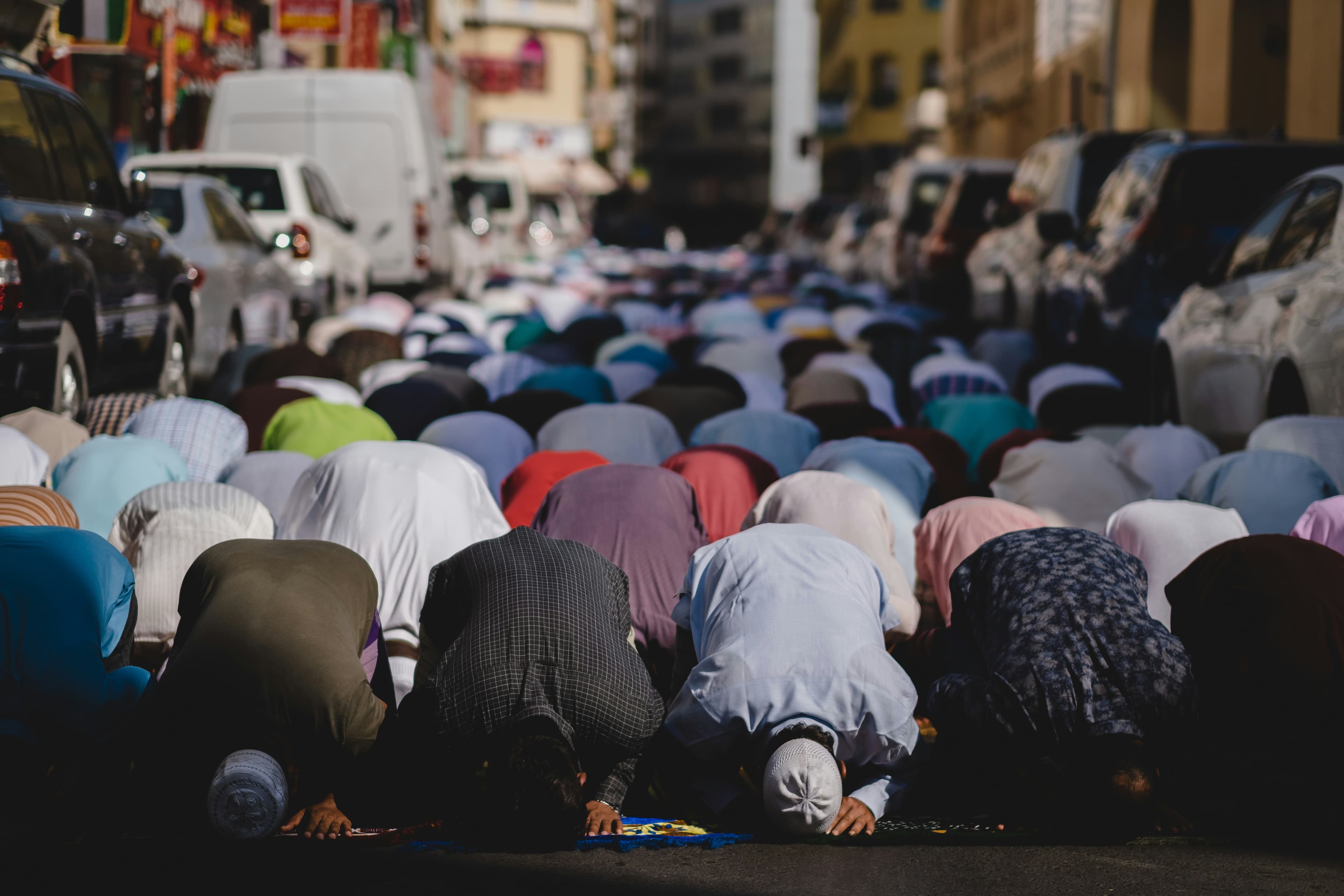 A congregation of Muslim men in sujud during outdoor Salah on a city street